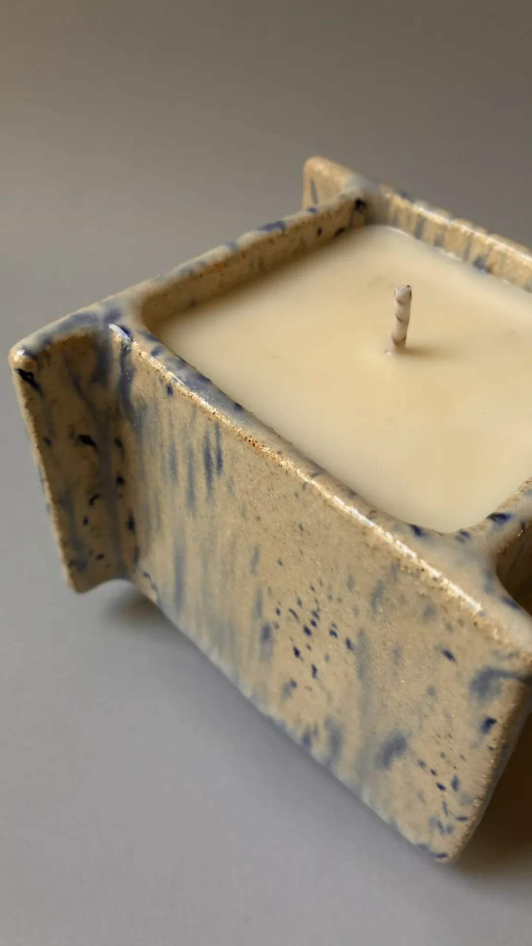 Détail de la surface en grès émaillé Blau Graniti, de la cire de soja vegan et de la mèche en coton.