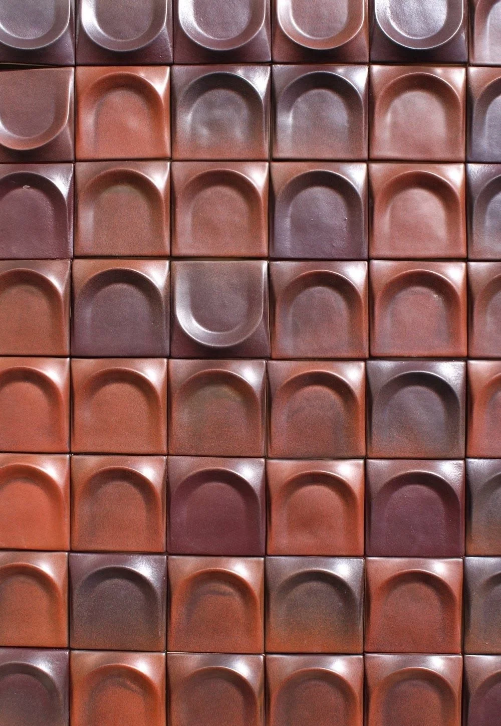 Carreaux de céramique oxblood disposés en grille répétée.