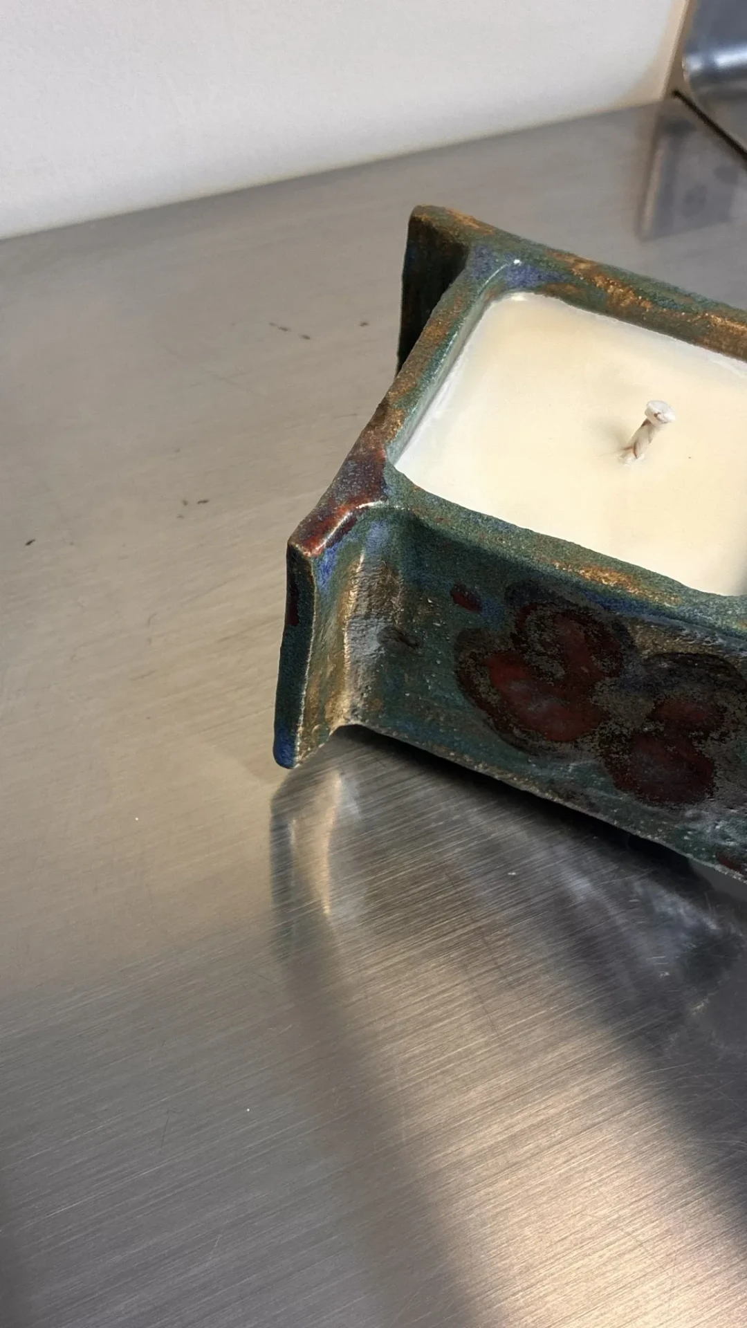 Bougie en céramique émaillée La Fille sur une surface en acier.