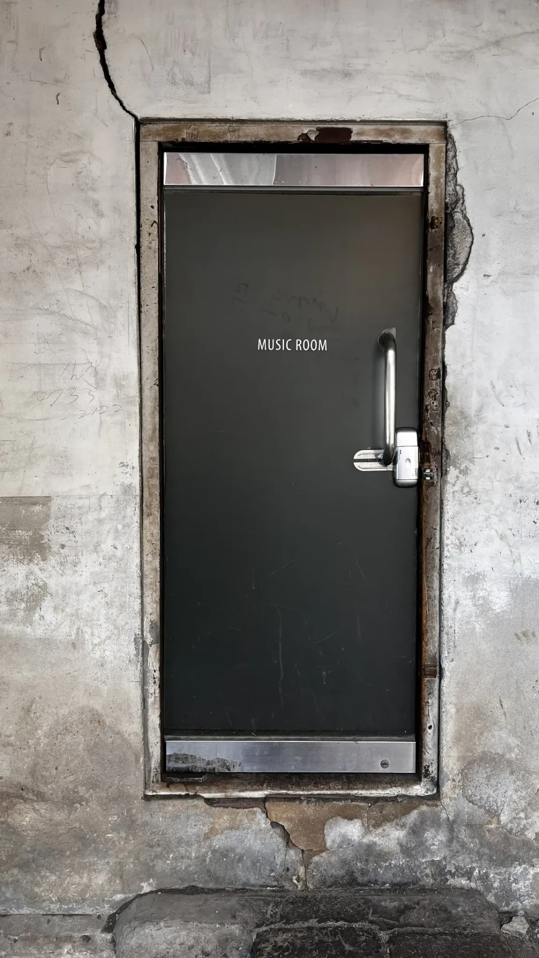 Dark door marked Music Room set into a weathered concrete wall.