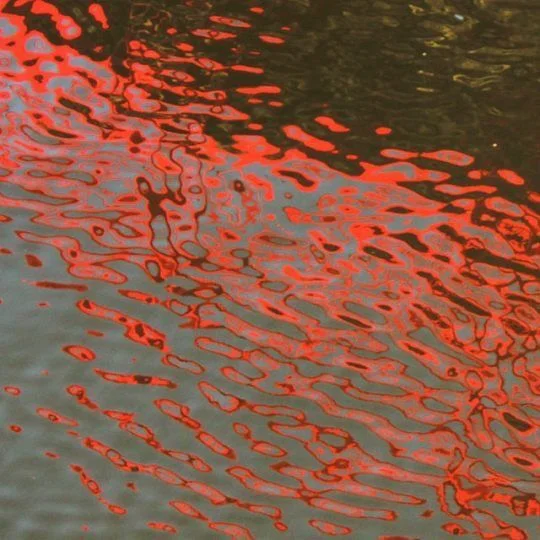 Reflets rouges ondulant à la surface de l’eau.
